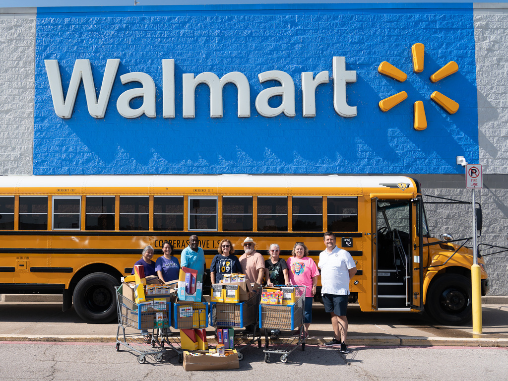 A group of people in front of a school bus smiling