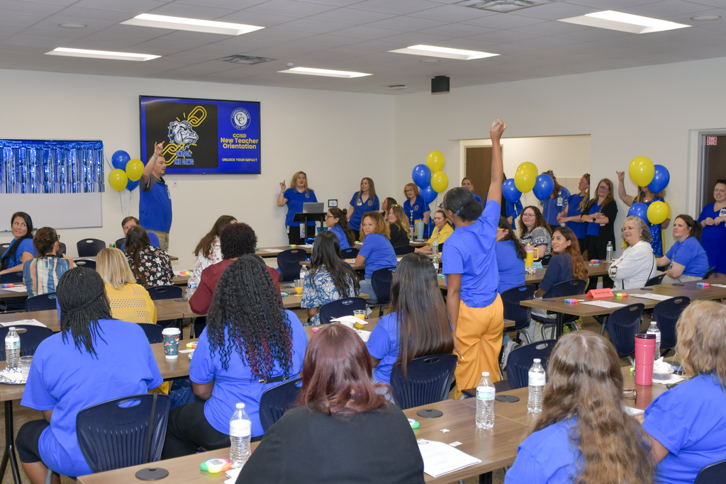 Woman standing up with hand raised in room full of people