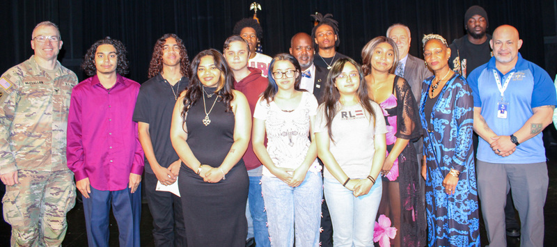 A group of adults and students smiling holding awards
