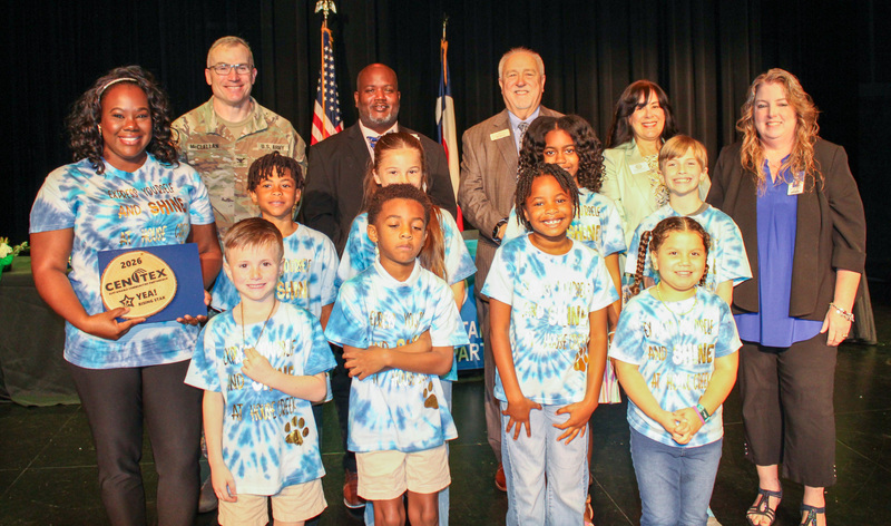 A group of students and adults smiling and holding awards