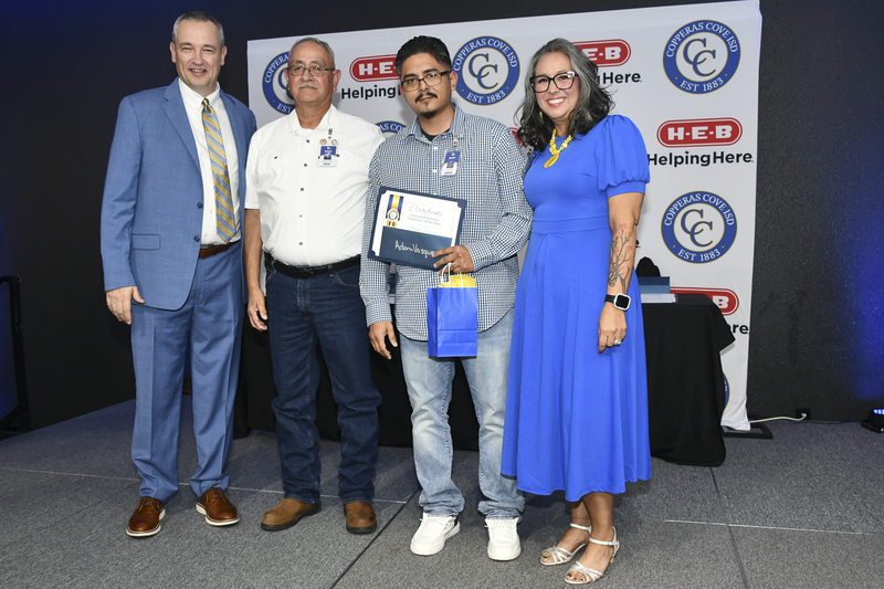 People smiling on a stage, holding awards