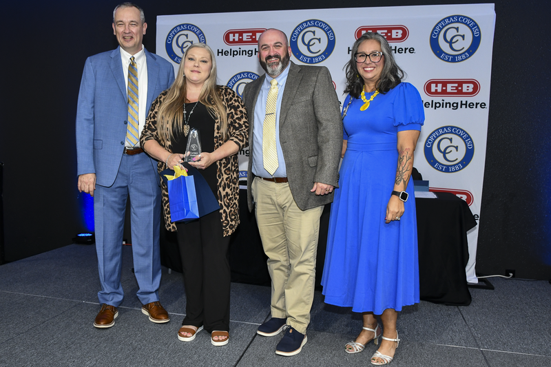 People smiling on a stage, holding awards
