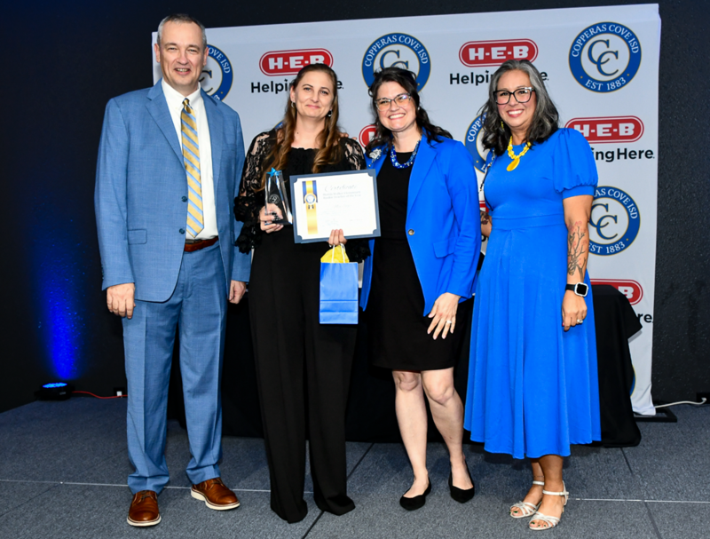 People smiling on a stage, holding awards