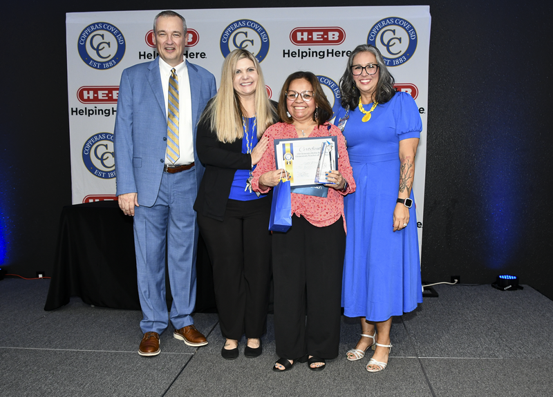 People smiling on a stage, holding awards