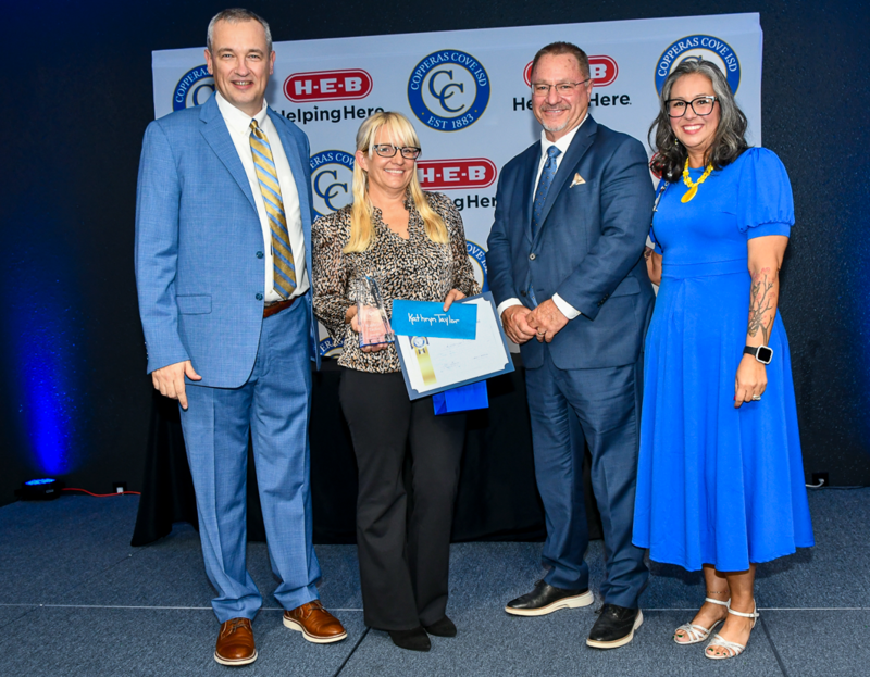 People smiling on a stage, holding awards