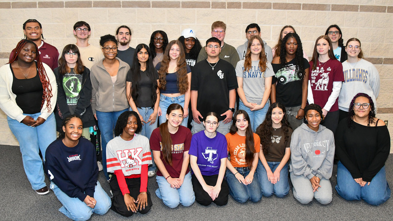 A group of students smiling in front of a wall