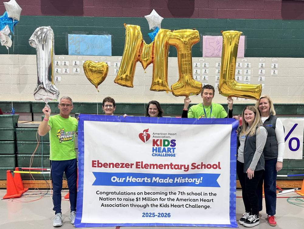 two men and four women behind a banner announcing $1 million dollars raised for AHA