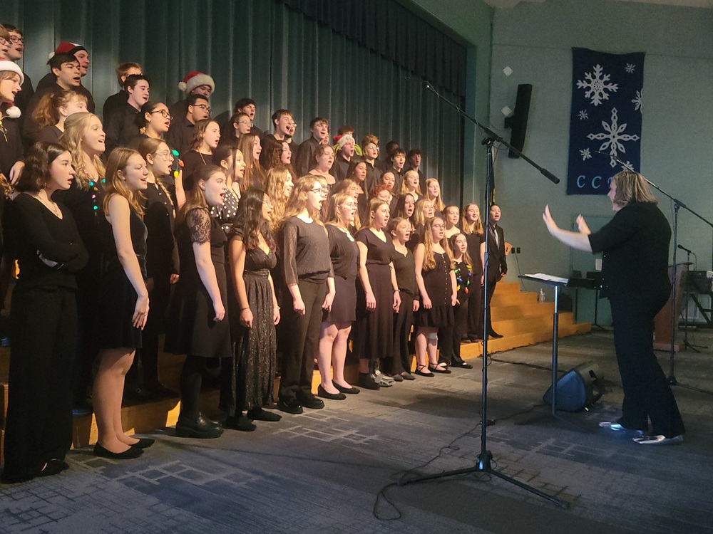 Choir director leads large group of high school students singing