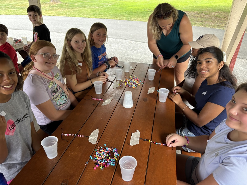 Girls making bead crafts at a picnic table