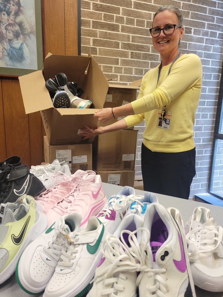 woman standing behind a table of shoes with more in boxes around her