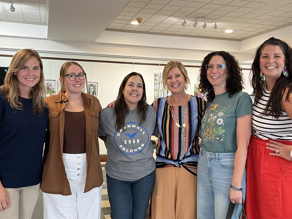 six women standing with arms around each other