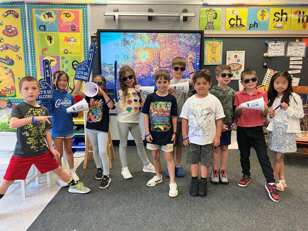 ten elementary boys and girls some wearing sunglasses and holding spirit items in a classroom