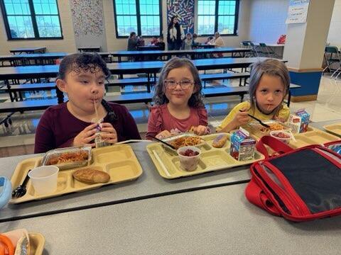 The elementary kids seated at school lunch table