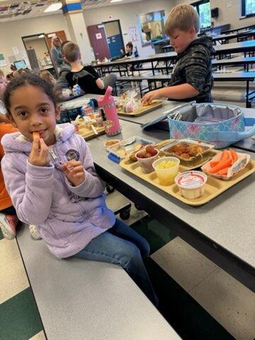 girl eating carrot stick at school lunch table