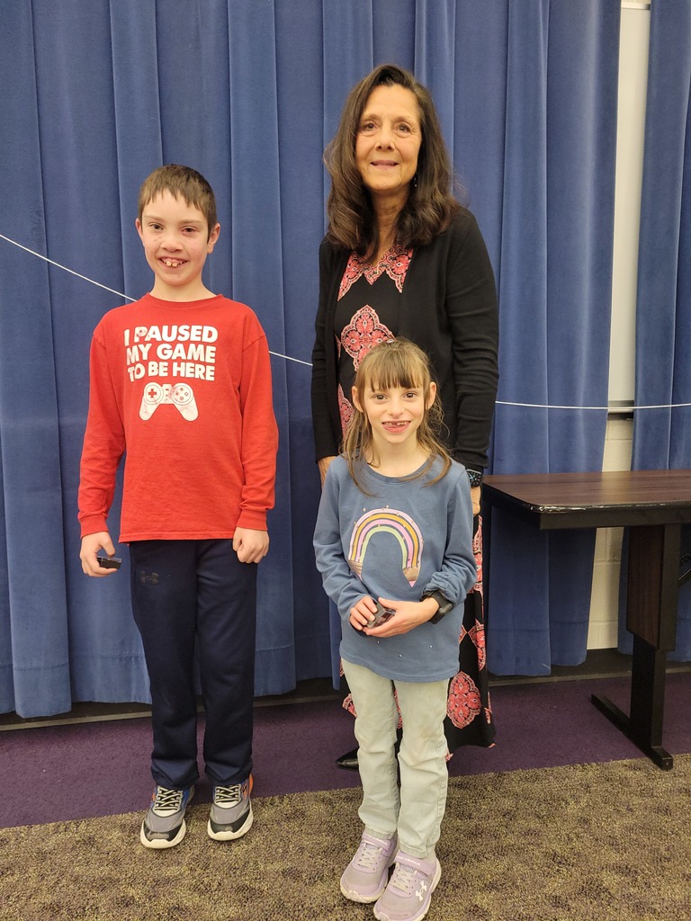 Woman with young boy and elementary age girl in front of a blue curtain