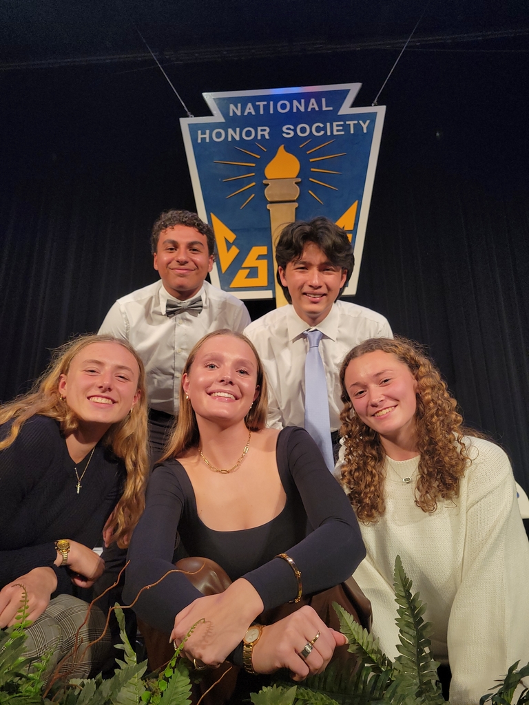 3 high school girls and two high school boys pose on a stage under the sign, National Honor Society 