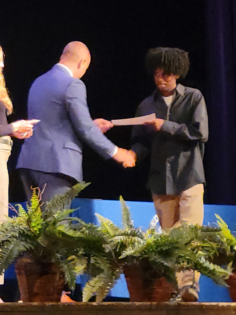 dark skinned high school boy accepts certificate from white male high school principal