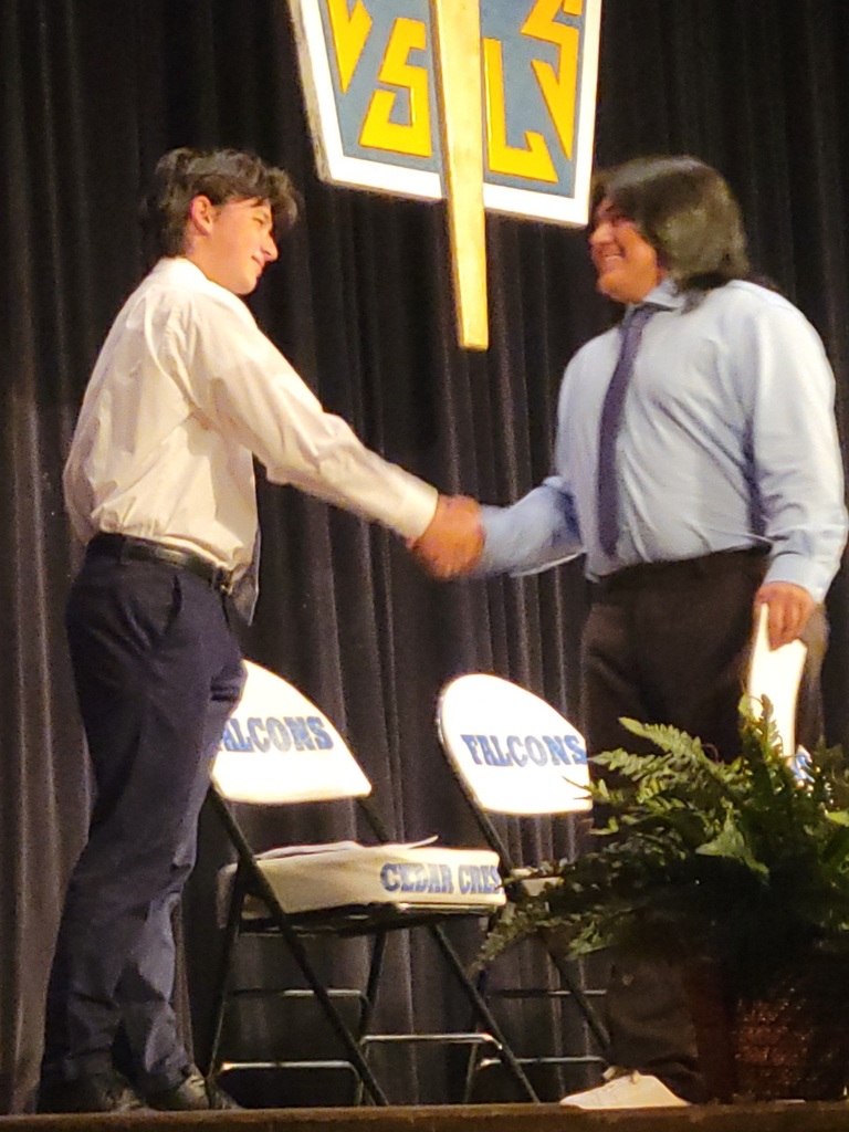 young men shaking hands under National Honor Society sign, on a stage