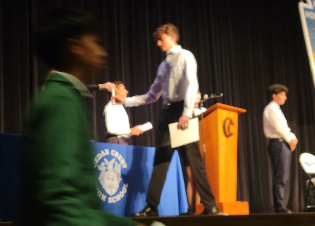 four well-dressed high school boys on a stage
