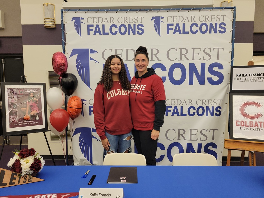 Two young women in front of a Cedar Crest Falcons backdrop