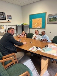 Adult man playing UNO with three students