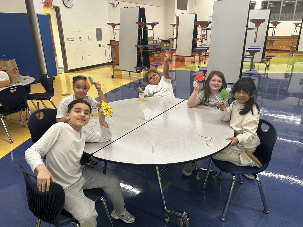 Five young students at a round table holding their paper craft