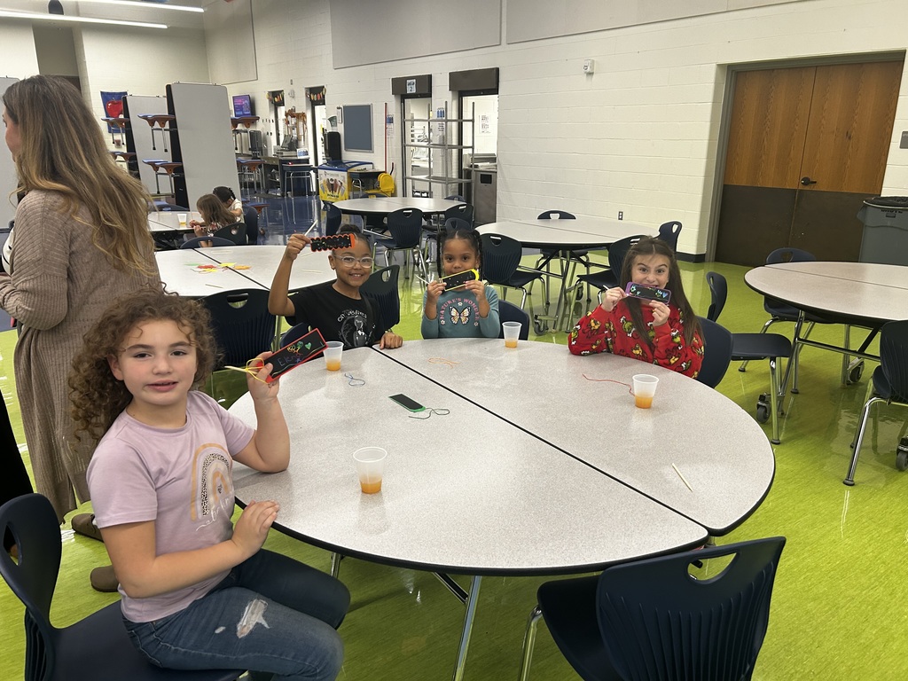 Four young girls at a round table holding their paper craft