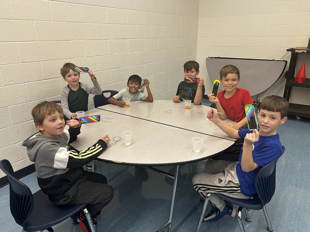 Six young boys at a round table holding their paper craft