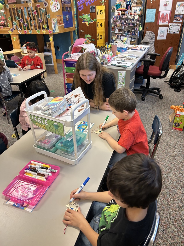 Female high school student  colors with two Kindergarten boys in their classroom