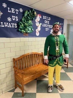 middle aged man in a green and yellow elf costume