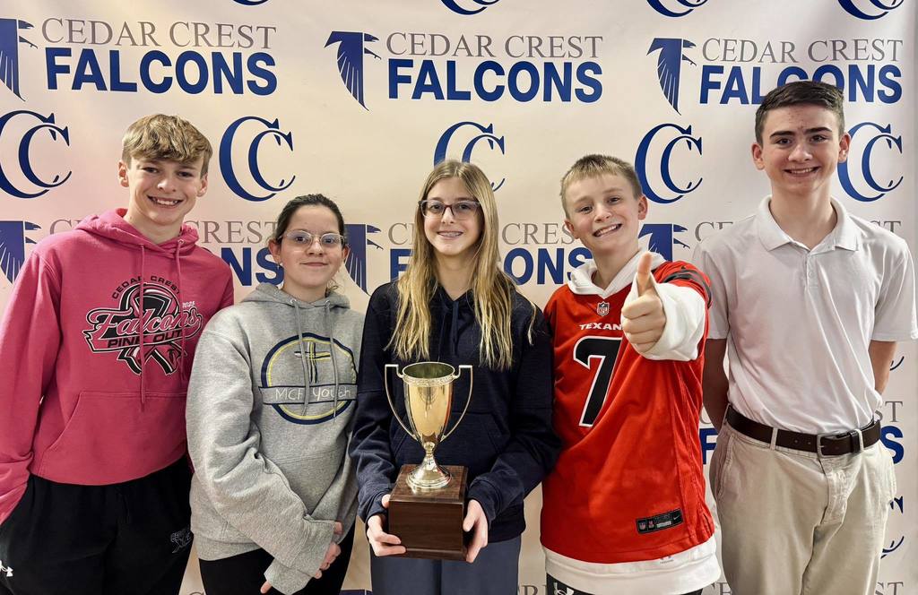 two girls and three boys standing in front of Cedar Crest Falcons logo screen with trophy
