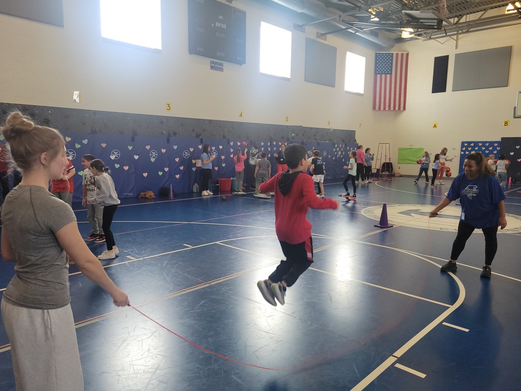 girl jumping the long rope in a gym with two volunteers turning the rope