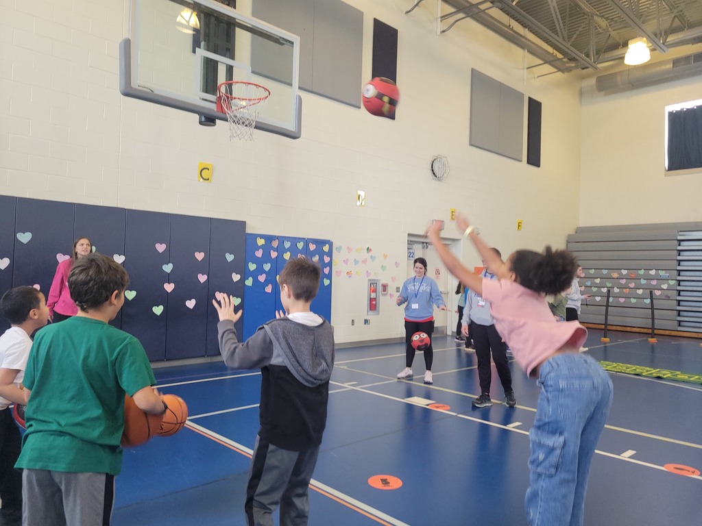 girls and boys shooting basketballs at the hoop in a gym