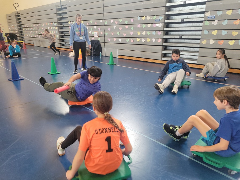 young boys and girls sitting on floor scooters play Tag