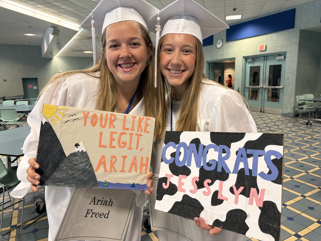 Two members of the Class of 2026 pose with signs made by students and staff