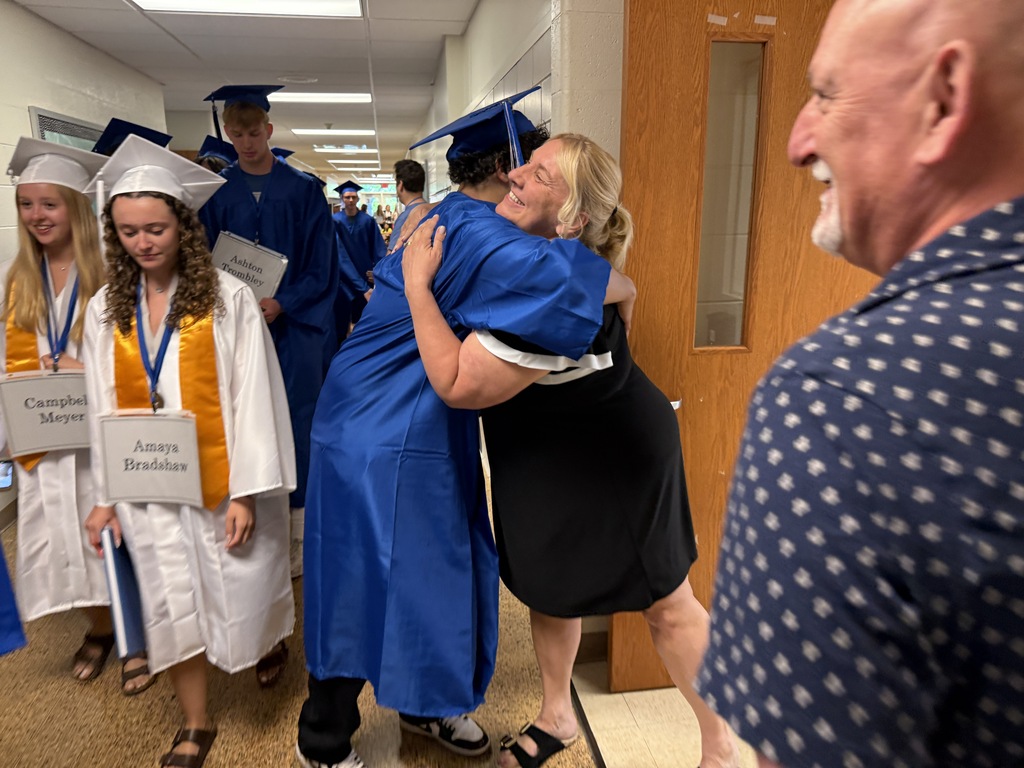 A graduating seniors receives a hug from their middle school teacher