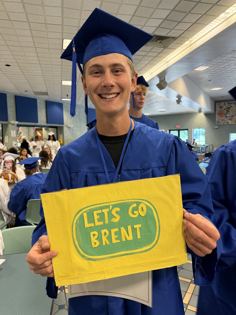 A graduating senior holds a sign created by students and staff