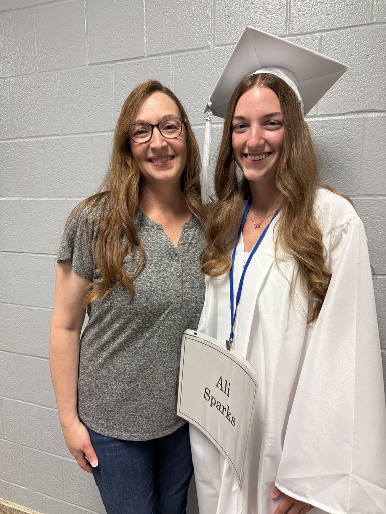 A staff member poses for a photo with a graduating senior