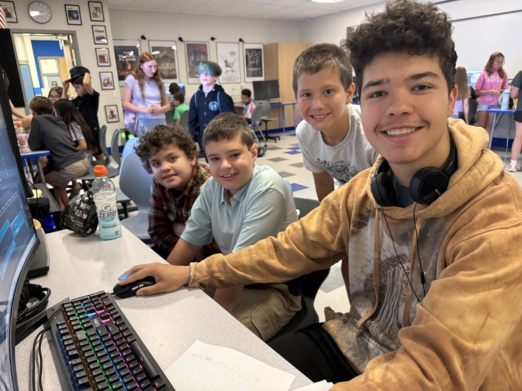 Students smile for the camera while editing a video