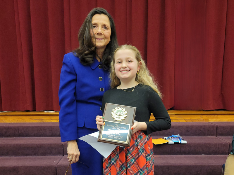 South Lebanon Elementary School Student of the Year holds her award plague in front of the auditorium stage with CLSD Board President Ruth Ann Schlegel