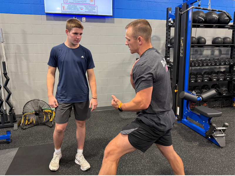 Cedar Crest High School strength and conditioning coach works with a student-athlete on proper training technique in the school’s weight room.