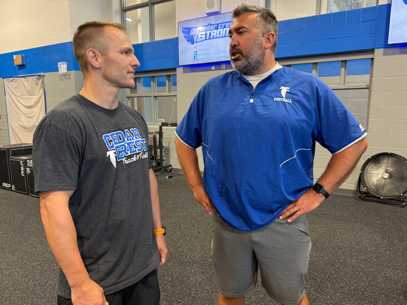 Cedar Crest High School coaches talk in the school’s renovated weight room, surrounded by strength-training equipment.