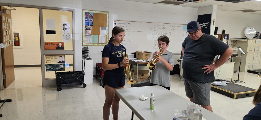 A 4th grader trying out a trumpet with help from a high school student. 