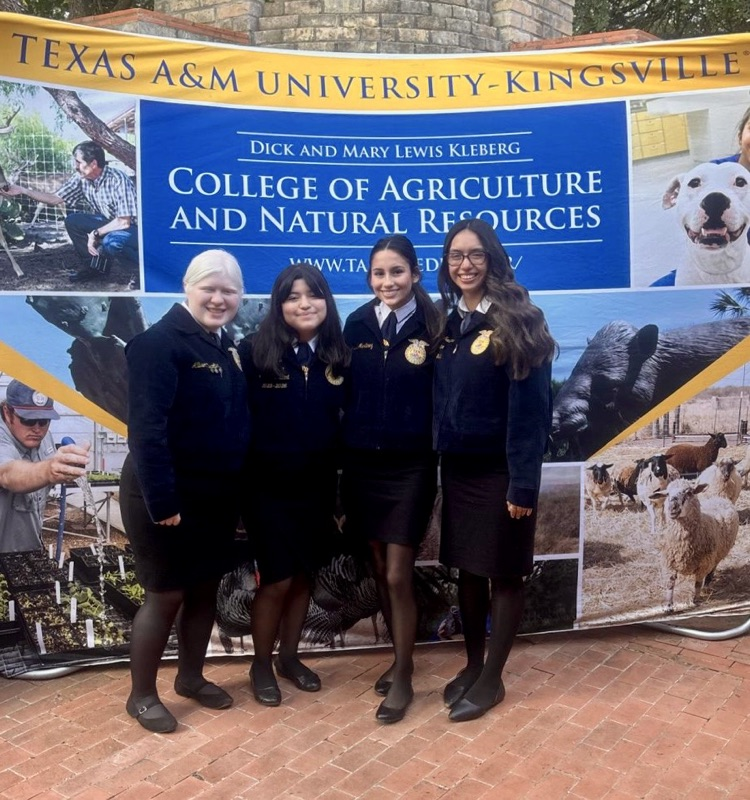 Seven Carroll FFA officers stand together in matching white shirts and jeans inside a large expo hall. They’re smiling after volunteering at Ag Awareness Days in Robstown.