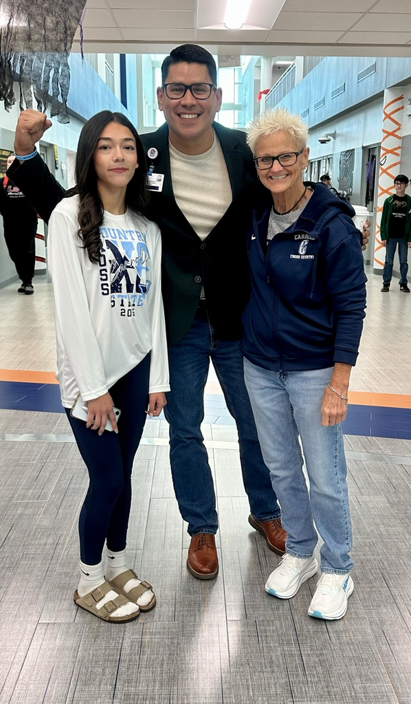 Alt Text: Eliana Lucio stands with Carroll staff and supporters wearing “Carroll XC State 2025” shirts, celebrating her state qualification with smiles, school spirit, and Tiger mascots.