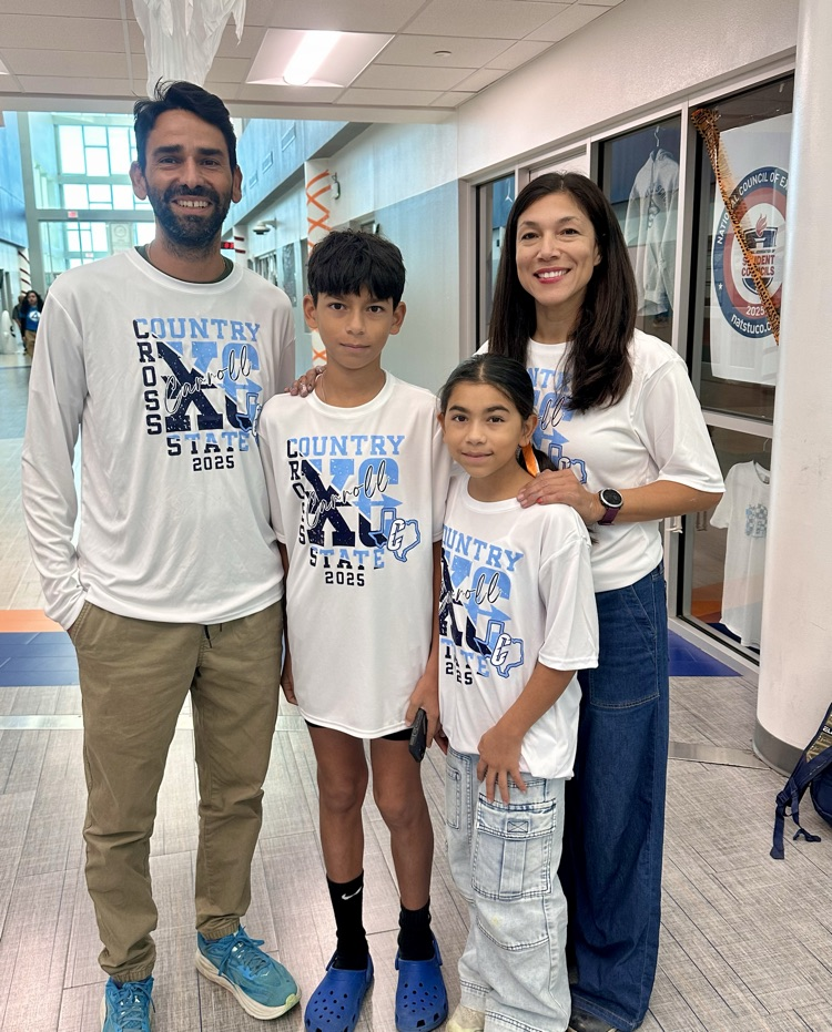 Alt Text: Eliana Lucio stands with Carroll staff and supporters wearing “Carroll XC State 2025” shirts, celebrating her state qualification with smiles, school spirit, and Tiger mascots.