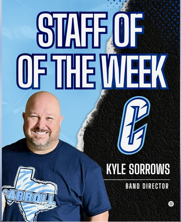 Carroll High School Band Director Kyle Sorrows, smiling and wearing a gold chain, poses with his band students in the rehearsal room, celebrating his recognition as Staff of the Week.