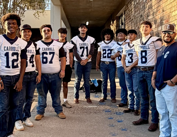 Carroll High School football players wearing white and blue jerseys greet elementary students with smiles and high-fives during morning arrival, showing school pride and encouragement.