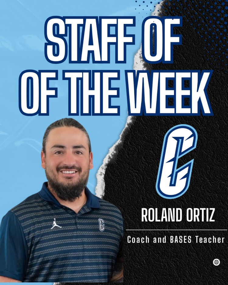 Coach Roland Ortiz smiles in front of a bright blue wall wearing a Carroll Football hoodie, gold chain, and backward cap. He holds a holiday popcorn tin and a Staff of the Week pass.