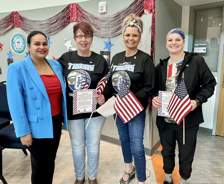 Alt text: Three Carroll High School teachers who are military veterans stand proudly holding American flags 